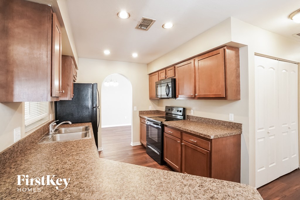 a kitchen with wood cabinets and granite counter tops and a black refrigerator