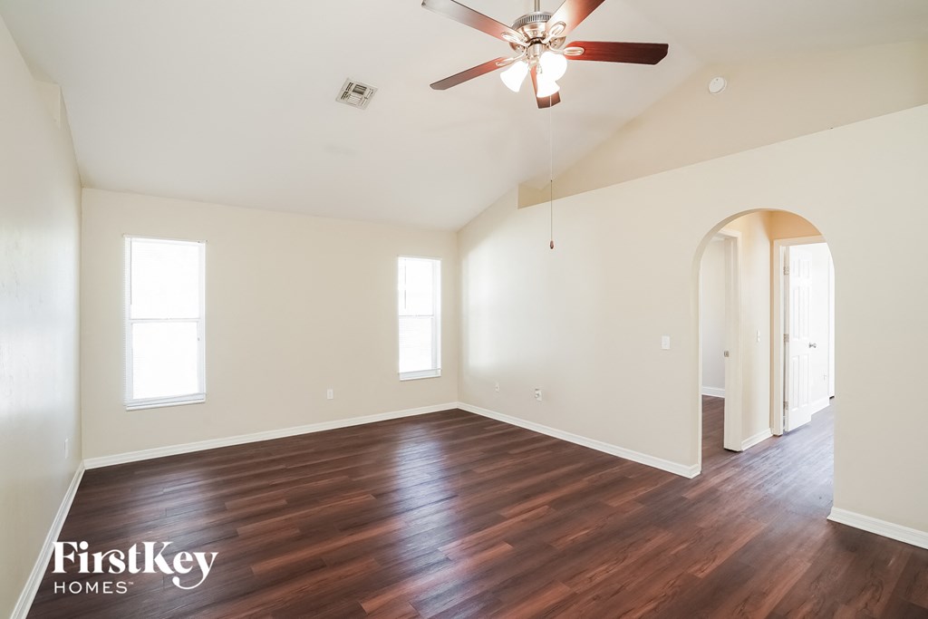 a living room with white walls and wood floors and a ceiling fan