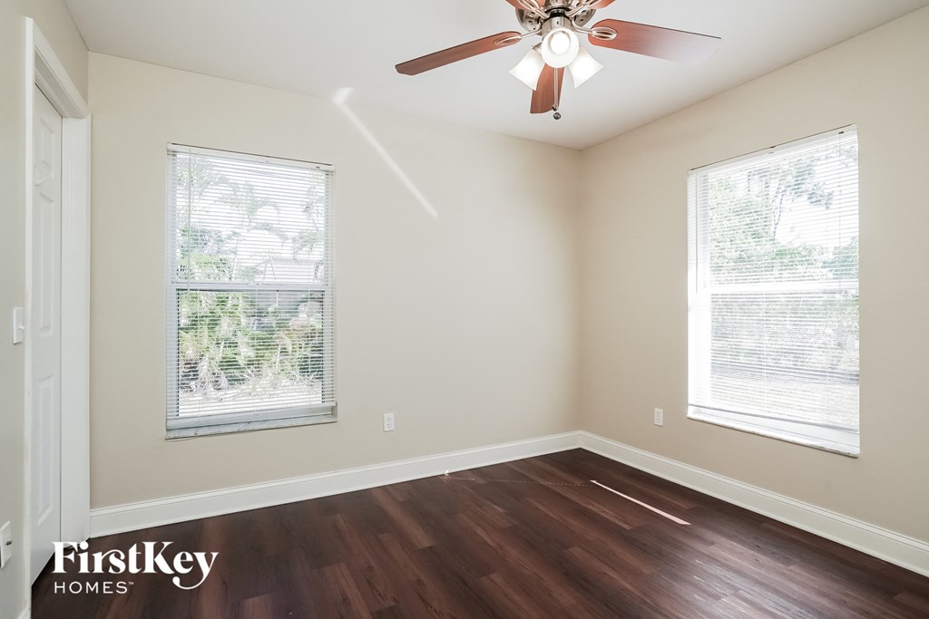 an empty room with a ceiling fan and two windows