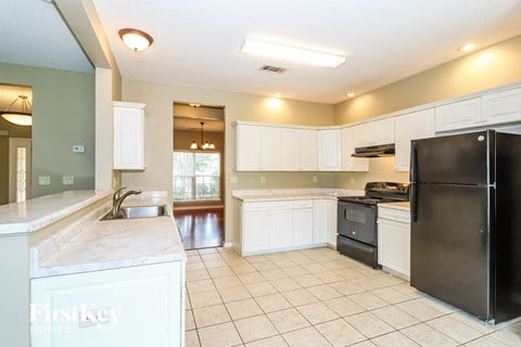 a large kitchen with white cabinets and black appliances