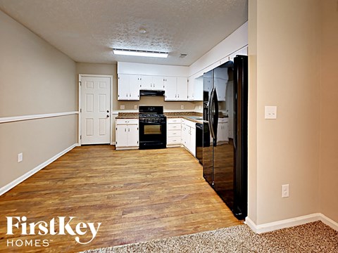 a kitchen with white cabinets and black appliances and a wood floor