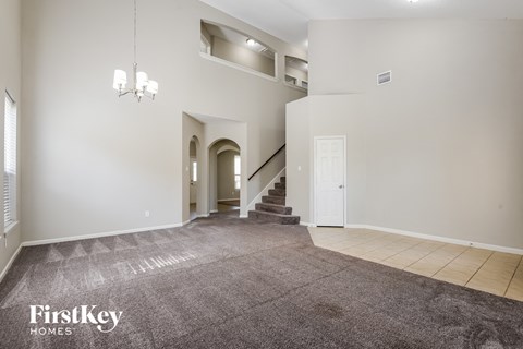 a living room with a carpeted floor and a staircase