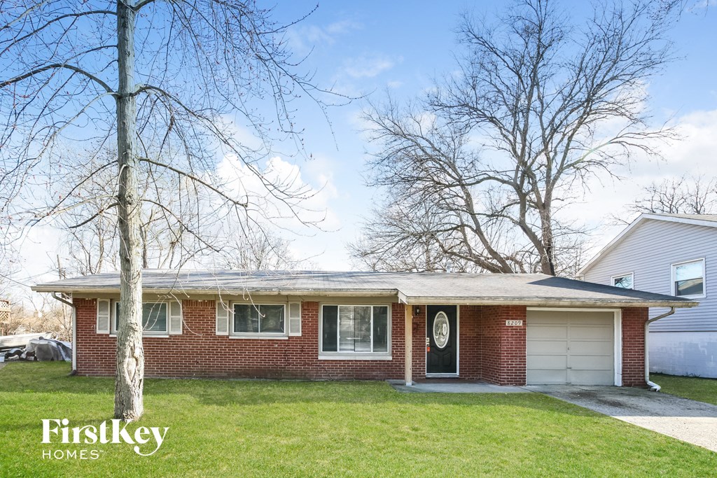 the front of a brick house with a white garage door