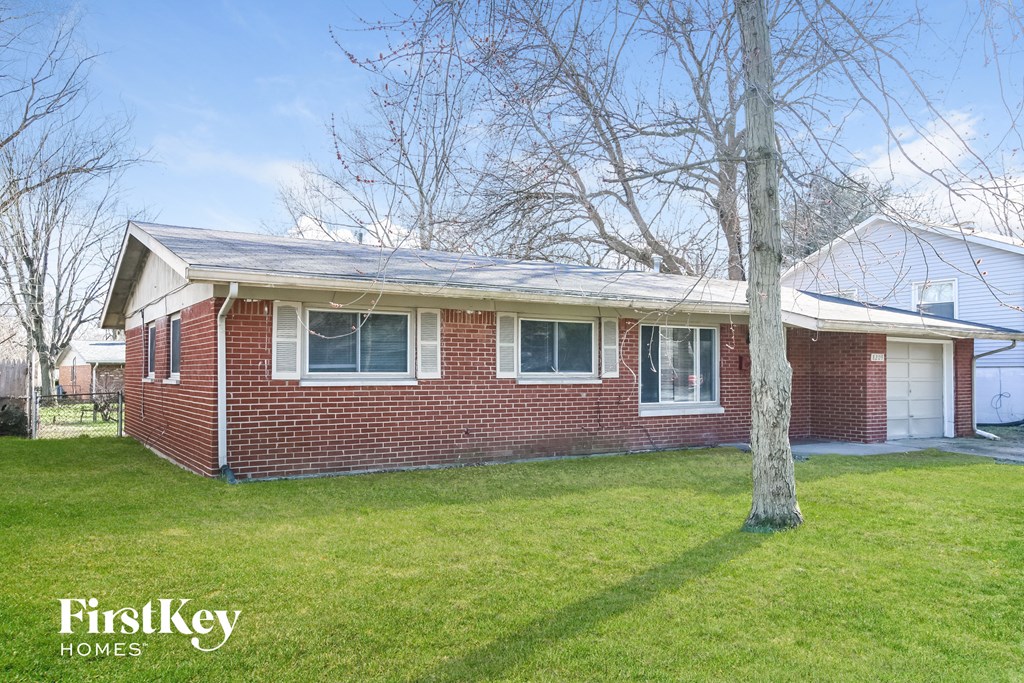 a brick house with a yard and a tree