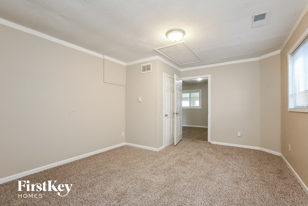 a spacious living room with carpet and a door to a hallway