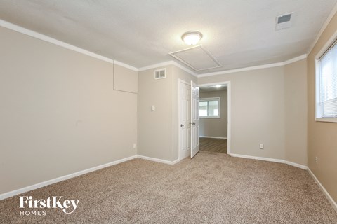 a spacious living room with carpet and a door to a hallway