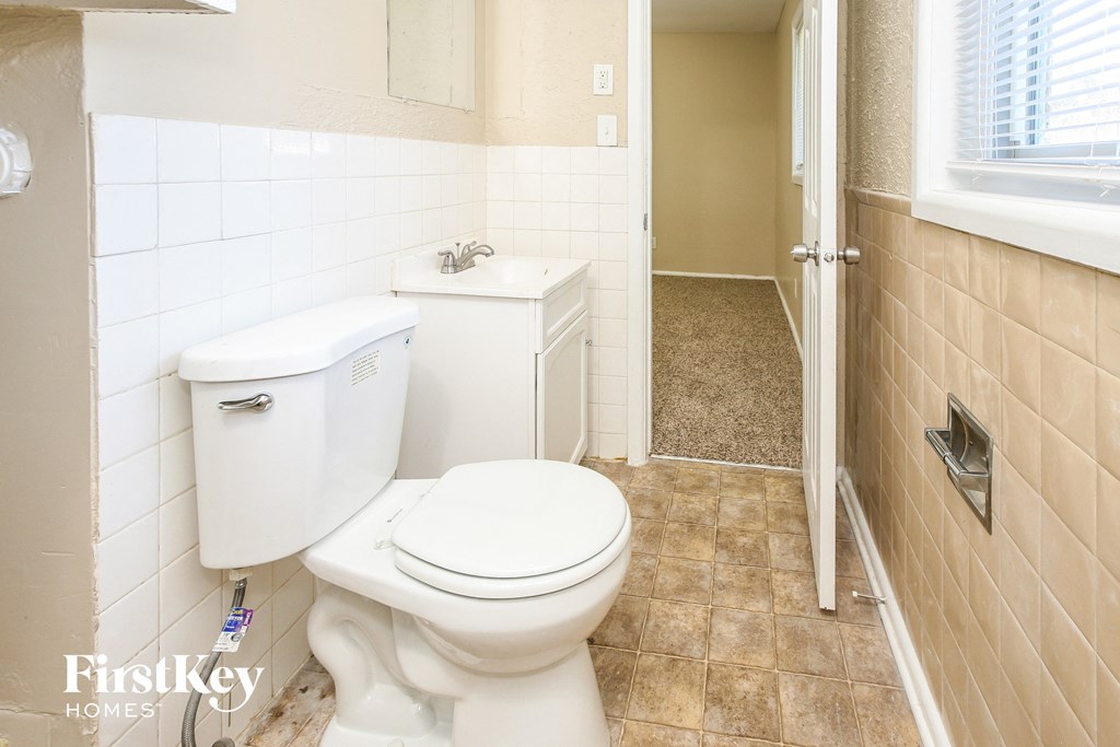 a bathroom with a toilet and a sink and a window
