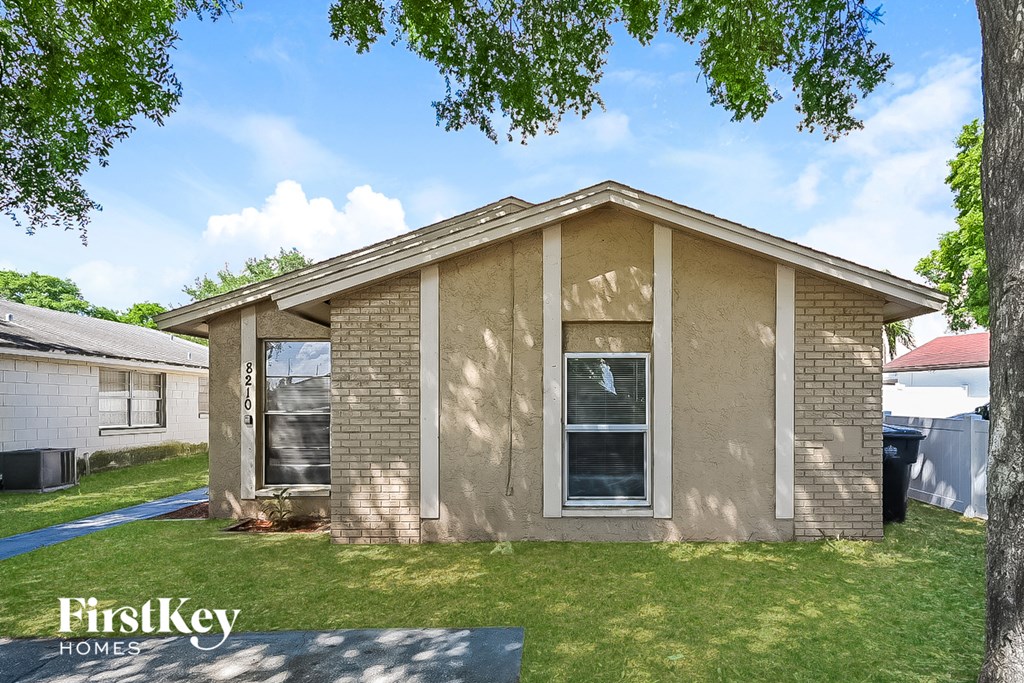 a brown brick house with a yard and a tree