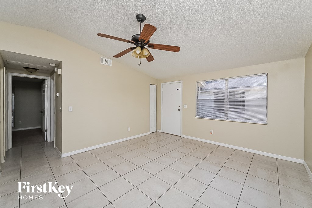 a living room with a ceiling fan and a tiled floor