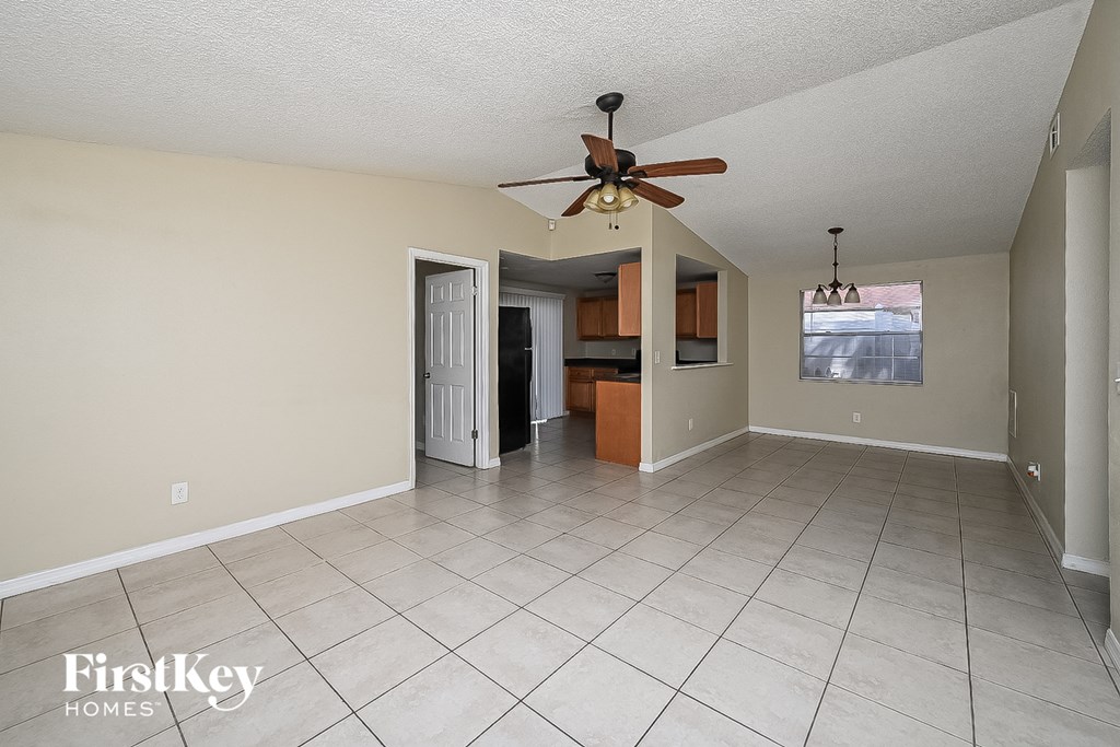 an empty living room with a ceiling fan and a tile floor