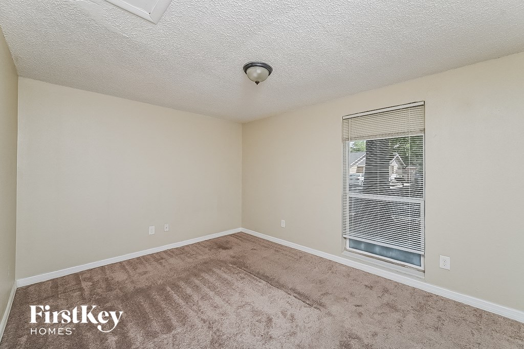 the living room of an empty house with a window and carpet