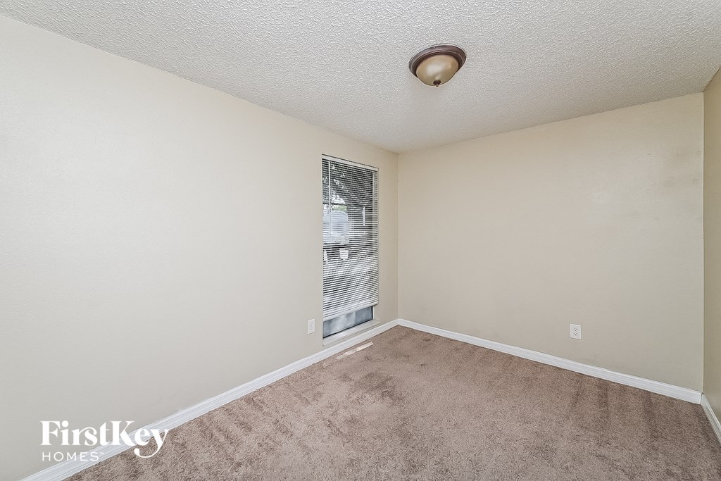 an empty living room with carpet and a window