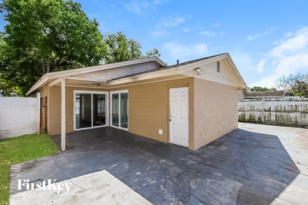a small tan house with a driveway and a white door