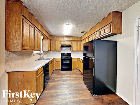 A kitchen with wooden cabinets and a black refrigerator.
