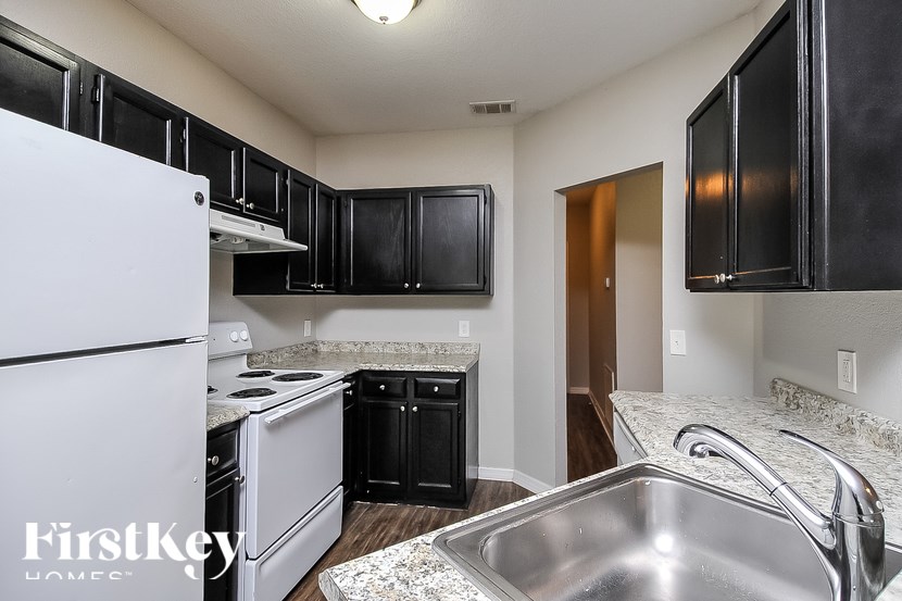 A kitchen with black cabinets and a white fridge.