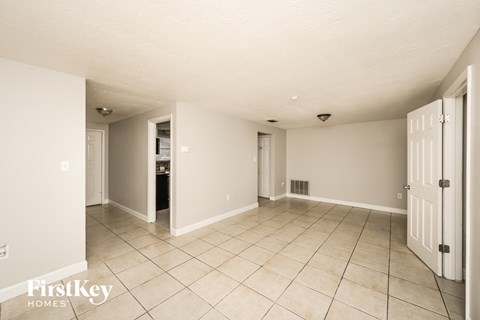 A spacious room with a tile floor and white walls, with a door on the right side.