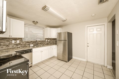 A kitchen with a stainless steel refrigerator and a black stove top oven.