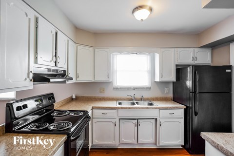 A kitchen with black appliances and white cabinets.