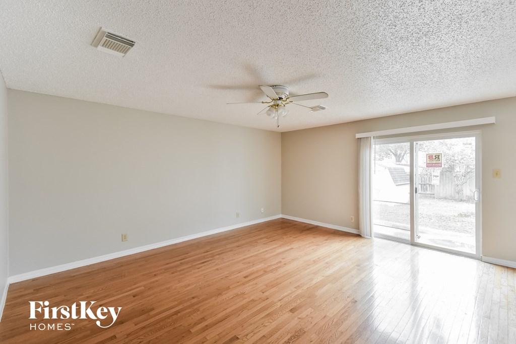 an empty living room with wood floors and a ceiling fan