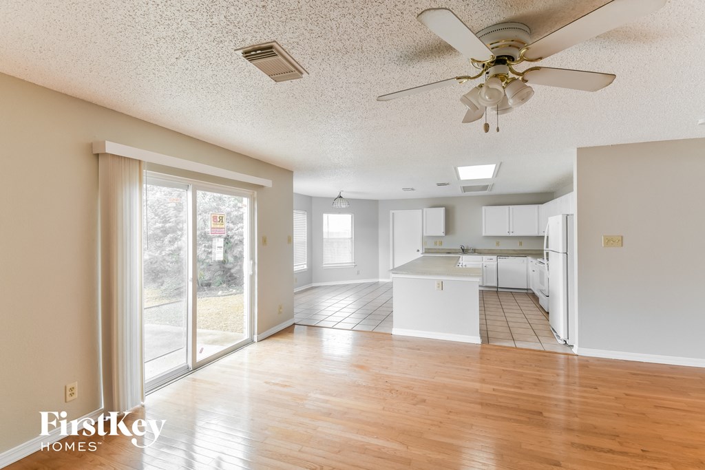 an empty living room and kitchen with a ceiling fan