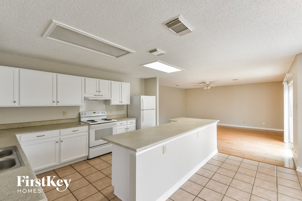 a kitchen with white cabinets and white appliances and a counter top
