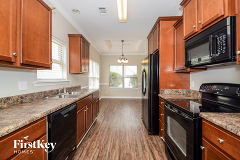 a kitchen with wood flooring and wooden cabinets and black appliances
