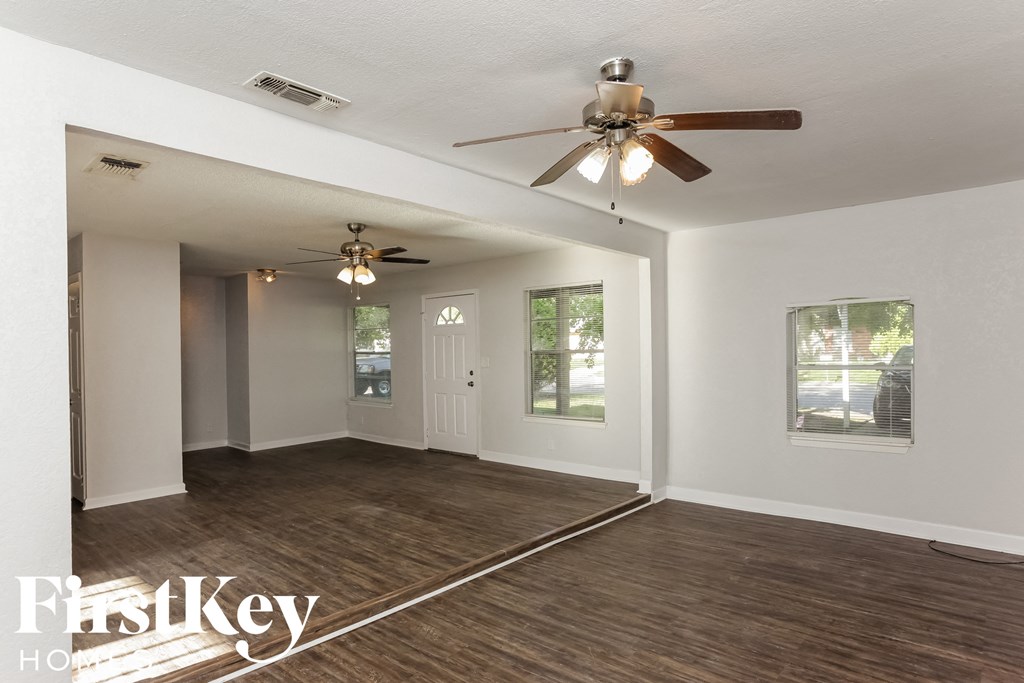 the living room of an empty house with a ceiling fan