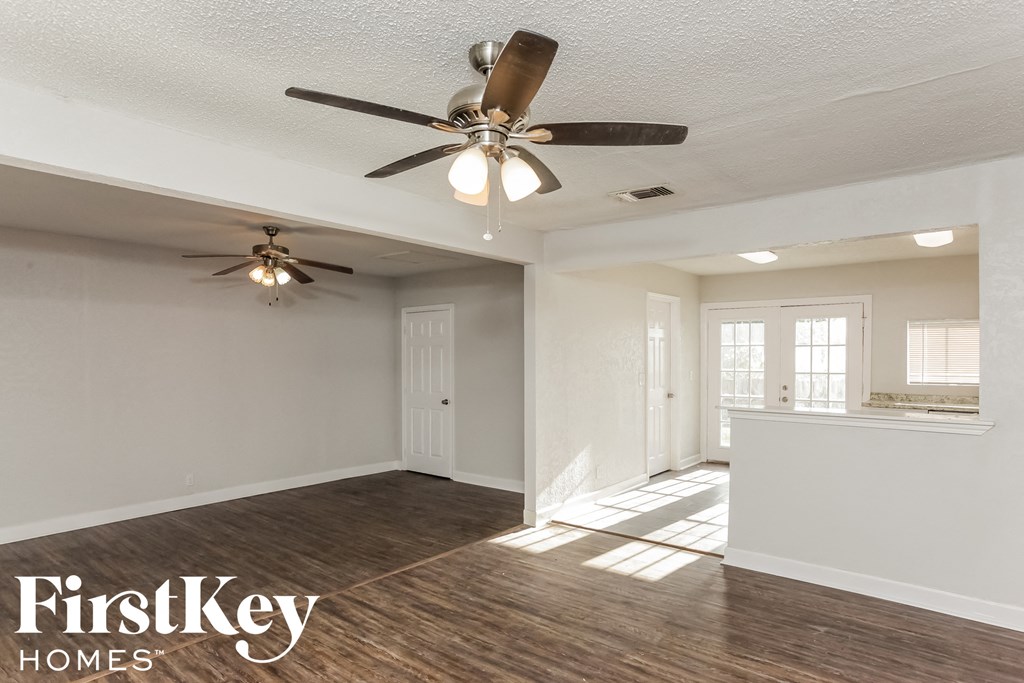 an empty living room with a ceiling fan