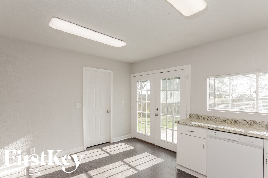 an empty kitchen with white cabinets and a door to a patio
