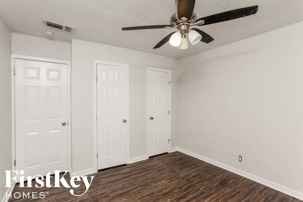 a bedroom with a ceiling fan and two doors