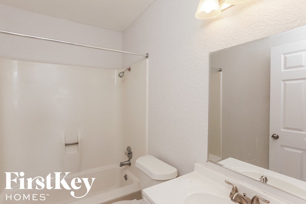 a white bathroom with a white sink and a toilet and a mirror