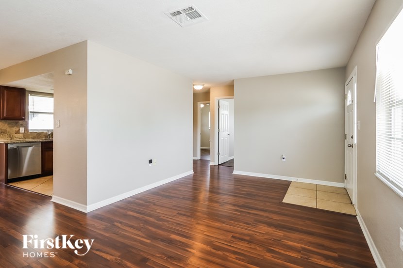 A spacious room with wooden floors and white walls, part of a home by FirstKey Homes.
