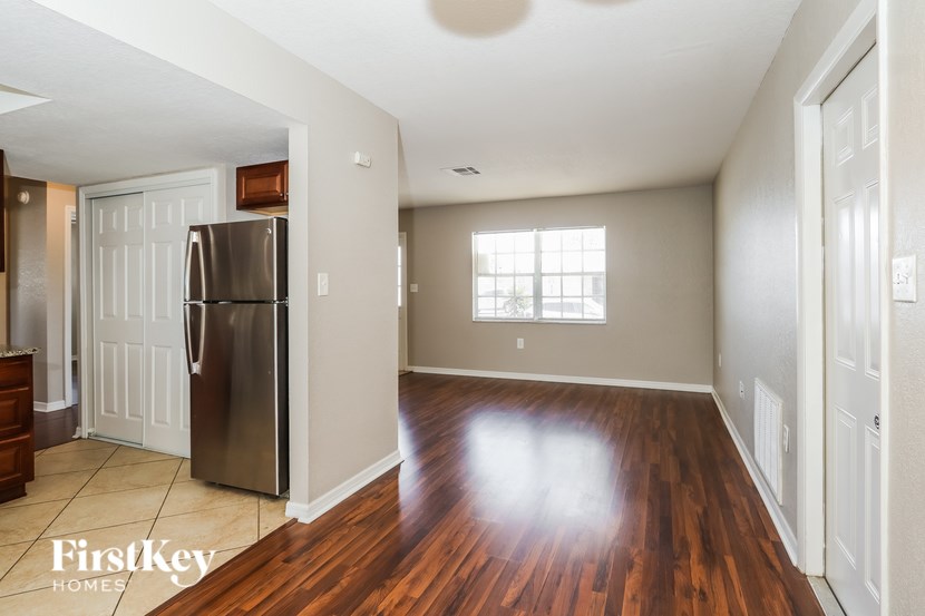 A kitchen with a refrigerator and wooden floors.