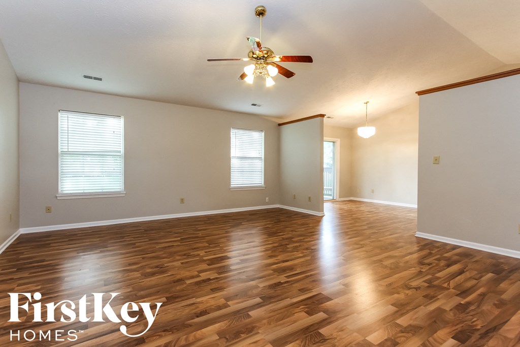 A spacious room with wooden floors and a ceiling fan.