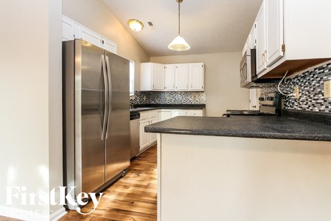 A kitchen with a stainless steel refrigerator and a black countertop.