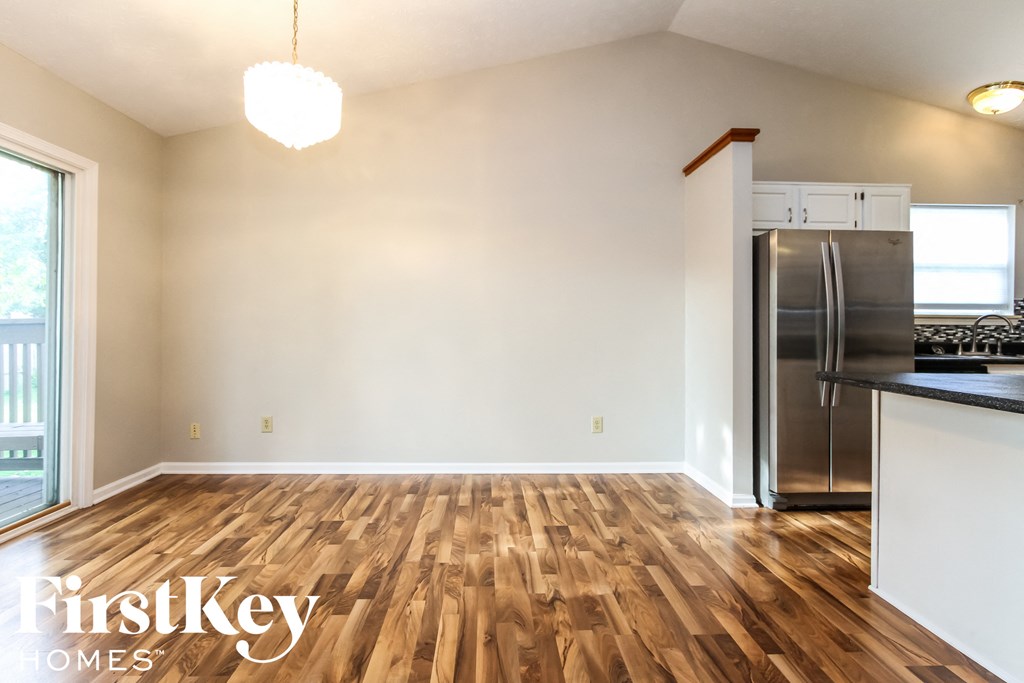 A kitchen with wooden floors and a stainless steel refrigerator.