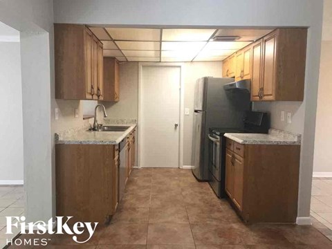 A kitchen with brown cabinets and a black refrigerator.