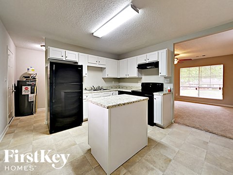 a kitchen with white cabinets and a black refrigerator
