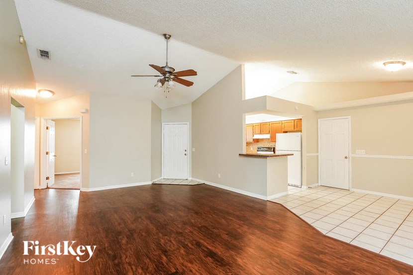 A spacious room with a wooden floor and a ceiling fan.