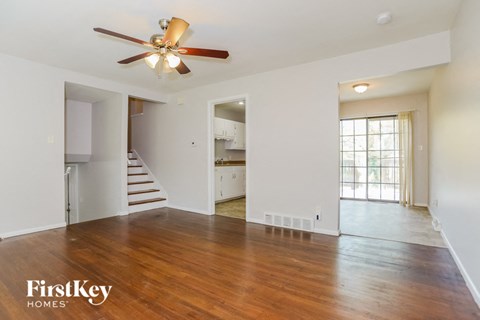 A spacious room with a wood floor and a ceiling fan.