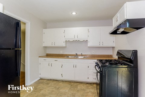 A kitchen with white cabinets and a black fridge.