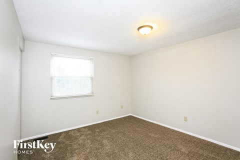 the living room of a house with carpet and a window