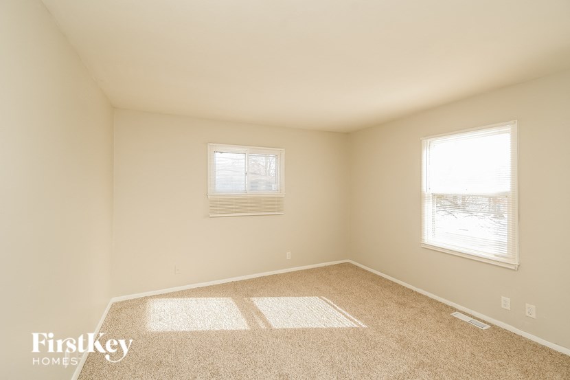 A room with a carpeted floor and two windows.