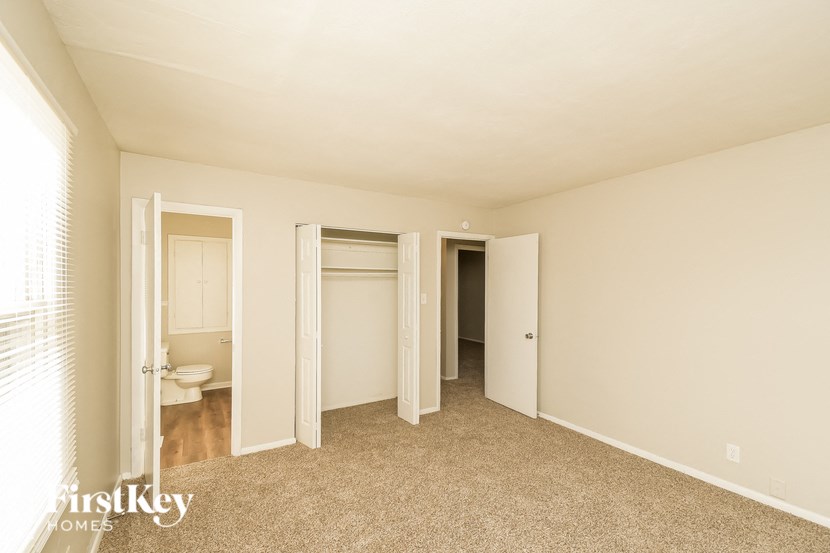 A carpeted room with a toilet in the corner and a FirstKey Homes logo.