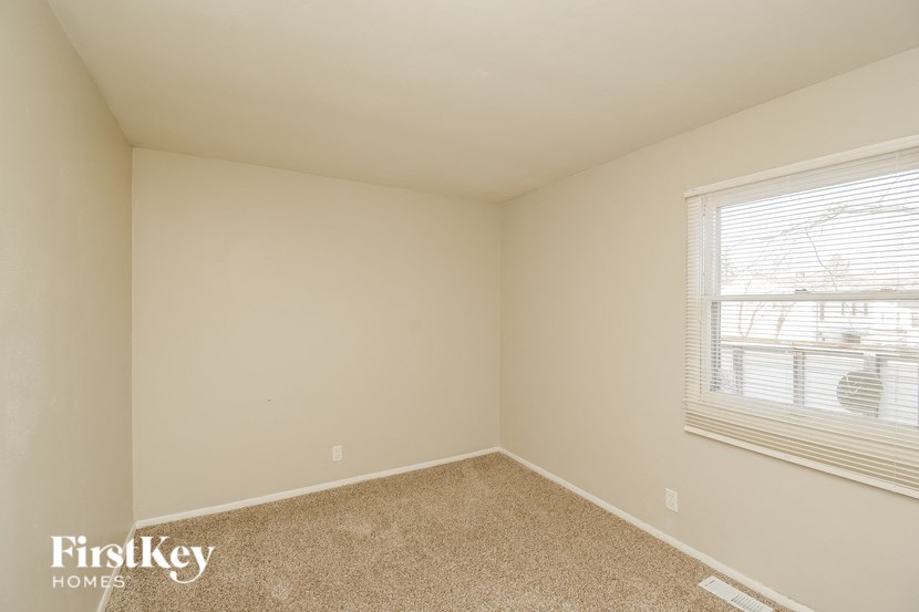 A room with a window and a carpeted floor.
