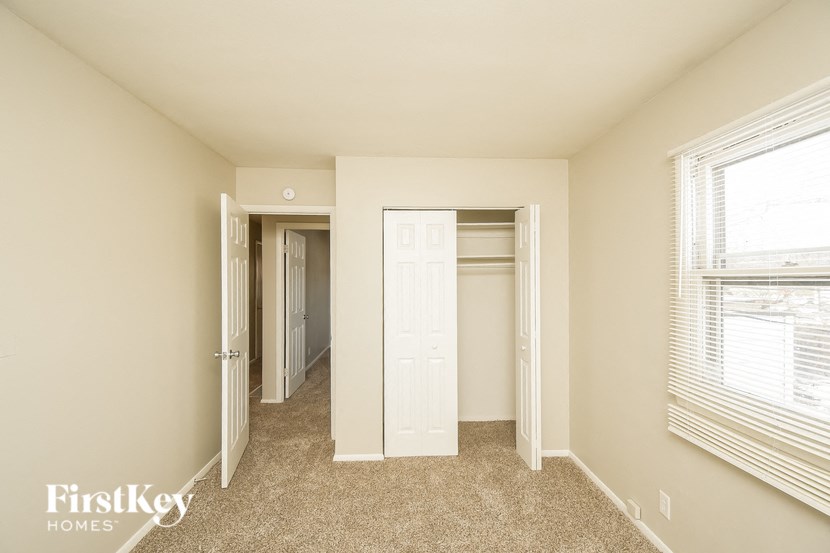 A carpeted hallway with a door on the left and a window on the right.