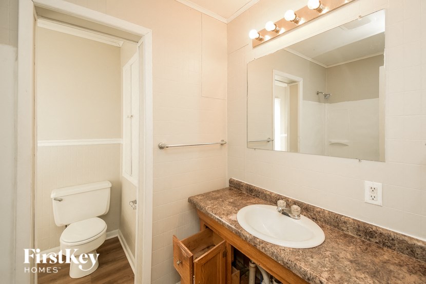 A bathroom with a toilet, sink, and mirror.