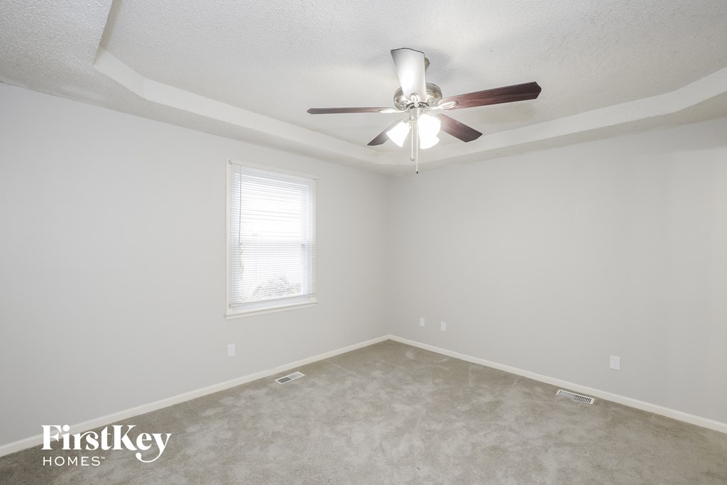 a bedroom with white walls and a ceiling fan