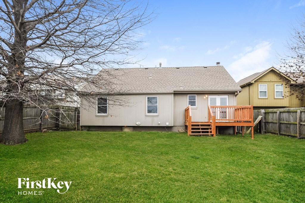 a backyard with a house and a deck and a tree