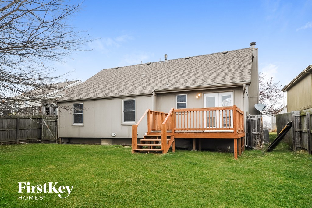 a backyard with a deck and a tan house